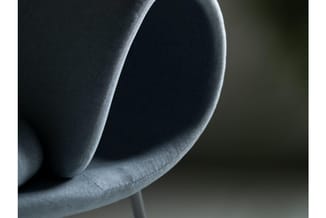 Grijze stoel met afgeronde rugkussens, detail van zacht gestoffeerde zitting en rugleuning.