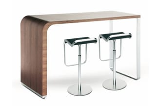 Hoog bartafel in walnoot hout met gebogen zijkant, twee zwarte barkrukken met zilveren onderstel op wielbasis.