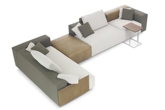 Modulaire hoekbank in beige en grijs met kussens, bijzettafel en loungestoel in U-vorm opstelling.