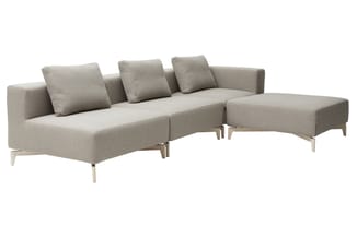 Grijze hoekbank met modulair ontwerp, beige houten poten, drie zit- en één ligdeel, decoratieve kussens, minimalistische uits
