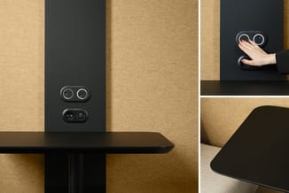 Zwarte akoestische wand met dubbele camera's en sensoren tegen beige/gouden akoestische panelen in kantooromgeving.