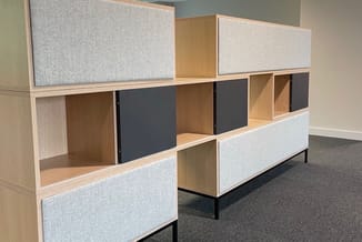 Modulaire kasten in kantoor met houten frame, grijze stofpanelen en donkerblauwe deuren, gerangschikt in twee rijen.