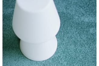 Wit design object met organische vorm op groenblauwe textielachtergrond, bovenaanzicht.