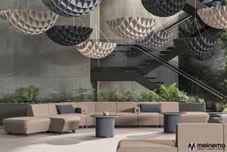 Modern lounge-zithoek met beige modulaire banken, zwarte bijzettafels, hanglampen in beige en zwart, groen planten en betonne