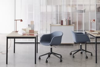 Modern kantoor met twee blauwe bureaustolen op wieltjes, twee zwarte bureaus met lichte bladen, rode bureaulampen en glazen w
