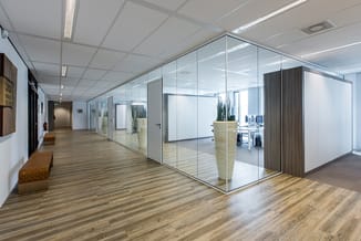 Modern kantoorruimte met glazen wanden, houten vloer, ingebouwde verlichting en minimalistisch meubilair in natuurlijke tinte