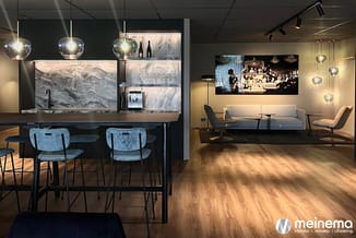 Moderne kantoorinrichting met zwarte bar met marmeren achterwand, blauwe barkrukken, hangende glazen lampen, grijze lounge-ba