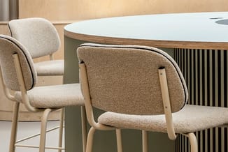 Twee beige stoelen met houten poten rond een moderne tafel met wit blad en groen onderstel in kantooromgeving.