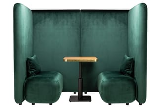 Groen fluwelen belcel met twee stoelen, houten tafel en hoge wanden voor akoestische privacy.