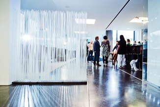Transparante verticale lamel scheidingswand in moderne kantoorruimte met bezoekers, polycarbonaat, wit-grijs, licht doorlaten