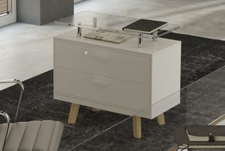 Witte nachtkast met twee laden en houten poten, op zwart tapijt. Glazen tafelblad bovenop met documenten en notitieblok.