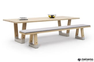 Houten vergadertafel met bijpassende zitbank met grijze kussens op betonnen voetjes. Tafelblad in natuurlijk houtkleur.