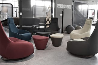 Loungeruimte met ergonomische zitmeubels in rood, blauw, beige en zwart, ronde poefs, moderne kantoorinrichting met glazen sc