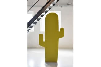 Groengeelkleurig cactus-vormig decoratief object in moderne kantoorruimte met trap op achtergrond.