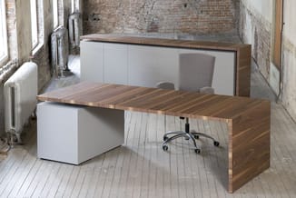 Moderne werkplek met houten bureau, witte kastenwand, grijze bureaustoel en radiator in industrieel interieur.