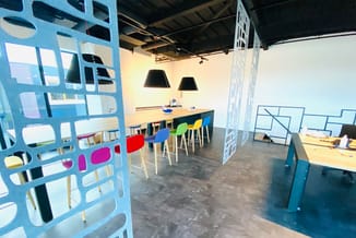 Moderne kantoorkamer met blauwe scheidingswanden, houten bartafel met kleurrijke stoelen (rood, geel, groen, blauw), zwarte h