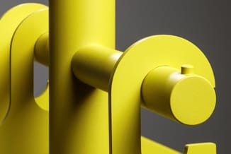 Geel kantoormeubel met cilindervormige elementen en ronde handgrepen tegen grijze achtergrond.