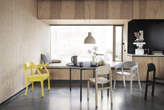 Moderne eetkamer met zwarte tafel, gele en houten stoelen, hanglamp, houten wanden en grote ramen met uitzicht.