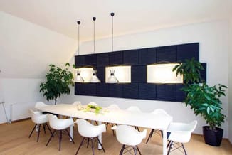 Moderne vergaderruimte met witte vergadertafel, witte ergonomische stoelen, zwarte wandpanelen met ingebouwde verlichting en