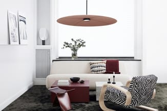 Moderne woonkamer met crèmekleurige ronde bank, zebra-patroon fauteuil, bordeauxrood bijzettafeltje, hangende bruine discolam