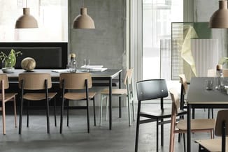 Moderne kantoorruimte met zwarte en houten stoelen rond grijze vergadertafels, betonnen wanden, hangende beige lampen en grot