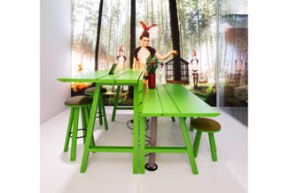 Groene houten vergadertafel met bijpassende barkrukken in een moderne ruimte met bossfotografie op de achtergrond.