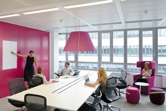 Modern kantoor met roze/fuchsia akoestische wandpanelen, witte vergadertafel, grijze bureaustoelen, roze hangend akoestisch s