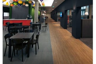 Moderne kantoorlounge met zwarte tafels, zwarte stoelen, rood bankgedeelte, houten vloer, zwarte wanden en gekleurde hangende