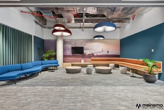 Modern kantoorinterieur met blauwe gebogen bank, houten lounge-banken, grijze poef-zitjes, hangende design-lampen en vliegtui