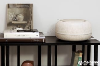 Zwart houten kastmeubel met open vakken, zwart bovenblad met gestapelde boeken en roomkleurig decoratief object.