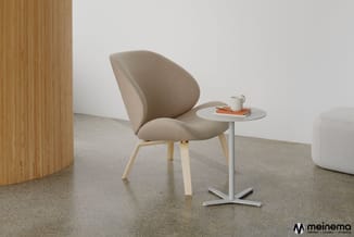 Beige stoel met organische vorm en houten poten naast wit bijzettafeltje met metalen onderstel in minimalistische kantoorruim