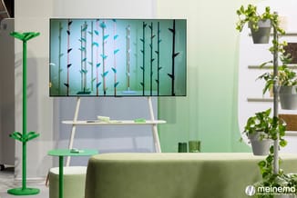 Groene kantoorruitruimte met wandscherm met blauw-groene vlindermotieven, wit design bureau, groen bijzettafeltje, hangplante