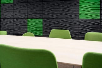 Vergadertafel met witte blad en groene stoelen tegen zwart-groene textiele wandpanelen