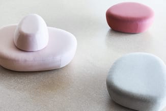 Vier zachte poefs in pastelkleuren (wit, roze en blauw) op neutrale ondergrond, waarvan één met afneembare bal-element.