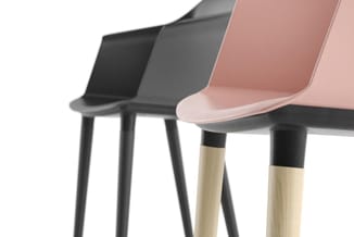 Drie stoelen in verschillende kleuren (zwart, grijs, roze) met kunststof zitting en houten poten met zwarte kap.