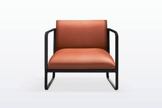 Moderne fauteuil met zwart metalen frame en oranje-rood gevoerde zitting en rugleuning.