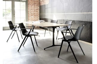 Moderne vergadertafel met zwart metalen onderstel en lichte tafelblad, omgeven door vier zwarte stoelen met houten poten in i