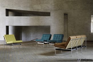 Vier design fauteuils met chromen frame in geel, turquoise en bruin leer in betonnen ruimte met inbouwkasten.