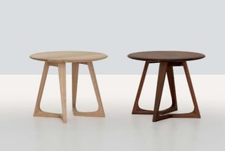 Twee ronde houten tafels naast elkaar: één in licht naturel hout, één in donkerbruin hout, beide met trapeziumvormige poten.
