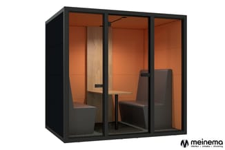 Zwarte belcel met oranje/bruin interieur, houten scheidingswanden, twee bruine stoelen en tafel, glazen schuifdeuren.