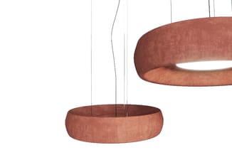 Hangende circulaire lamp in terracottakleurig stofmateriaal met doorzichtige suspensie, onderkant en bovenkant zichtbaar.