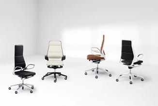 Vier moderne bureaustoelen in een rij: zwart met witte accenten, crème, bruin/cognac leer, en zwart met witte armleuningen, o