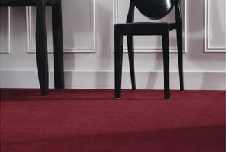 Zwarte moderne stoelen op rood tapijt tegen witte muur met panelering.