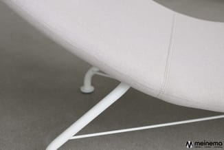 Detailafbeelding van witte stoel met grijze stoffen zitting en wit metalen pootframe op grijze vloer.