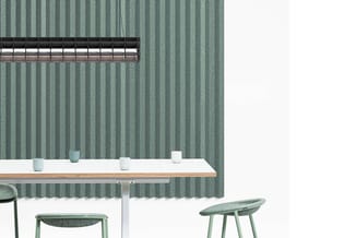 Moderne vergadertafel met wit blad en houten rand, groene stoffeerde stoelen, groene golfkartonnen akoestische wandbekleding,