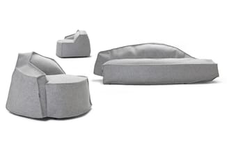 Drie grijze zitmeubels: twee ronde fauteuils en één langwerpige loungebank, alle in grijs stofmateriaal.