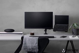 Moderne werkplek met wit bureau, zwarte bureaustoel, scherm, laptop, zwart toetsenbord, smartphone, notitieboek en potplant t