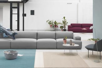 Moderne lounge met grijze modulaire bank, bordeauxrode zitbank, zwarte stoel, witte bijzettafel, turquoise en beige vloerkled