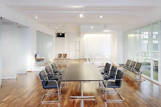 Moderne vergaderruimte met zwarte rechthoekige tafel, blauwe conferentiestoel met chroompoten aan beide zijden, houten vloer,