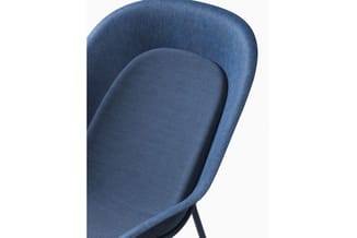 Blauwe bureaustoel met afgeronde rugleuning en zwart onderstel, details van zitting en ergonomische vorm zichtbaar.